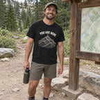 Man wearing the You Are Here T-Shirt at a trailhead map
